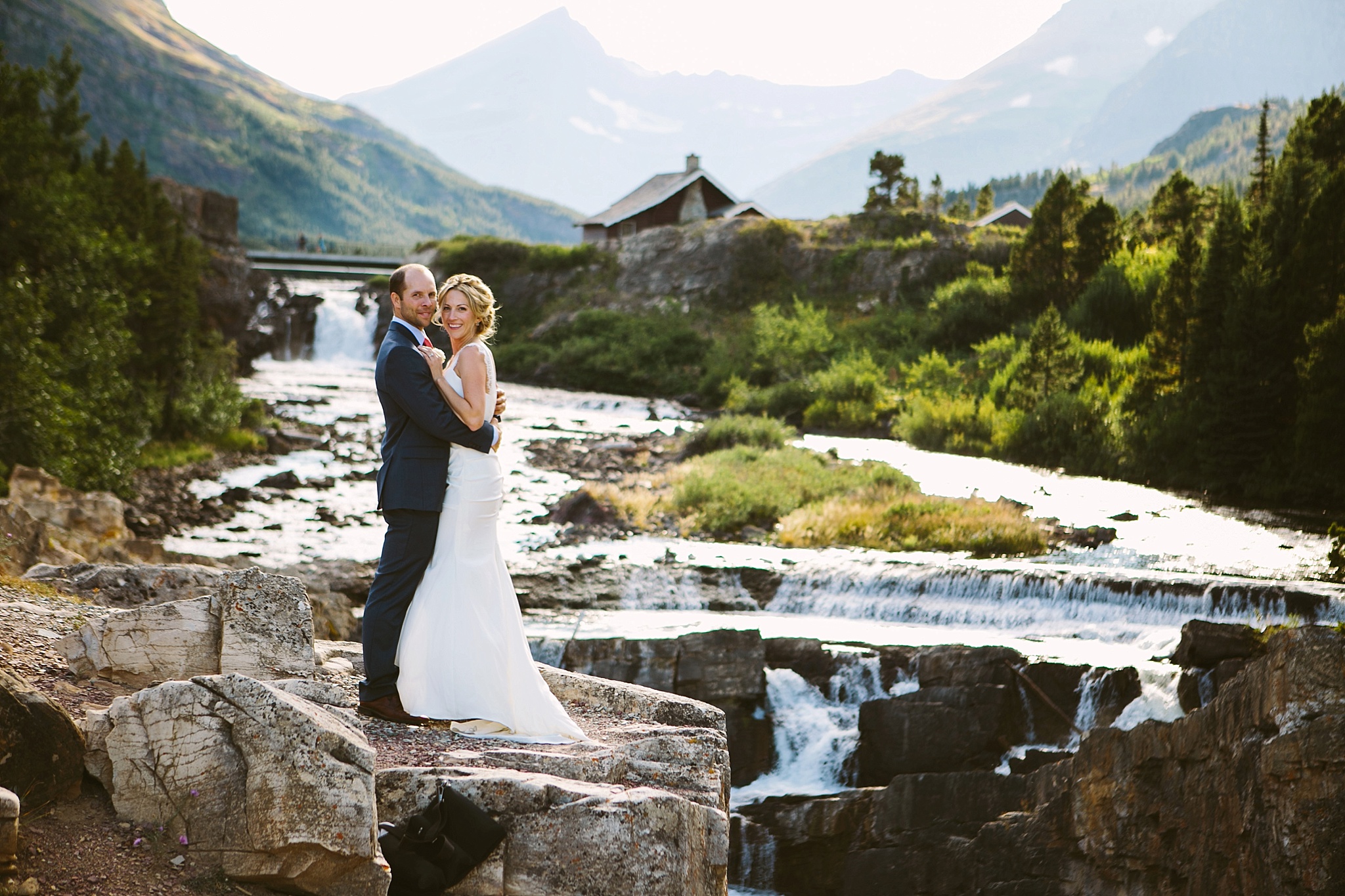 Many Glacier National Park Elopement Photos Bride and Groom Hugging above Waterfall