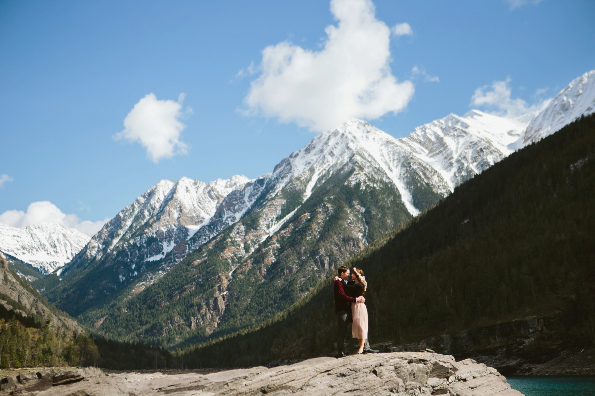 Missoula MT Mountain Engagement photos couple hugging on a cliff under snowcapped mountains