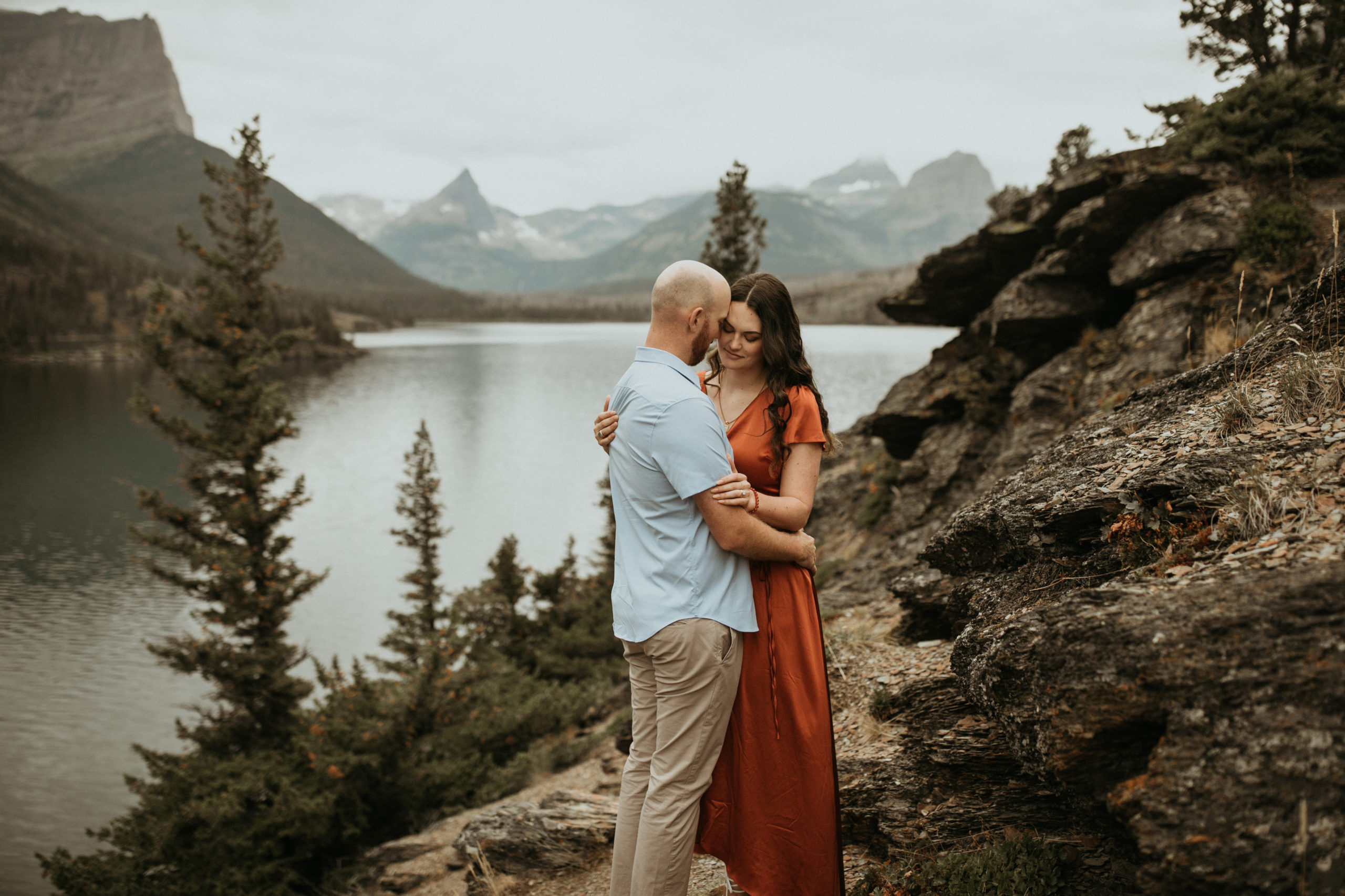 glacier national park fall engagement photos on a cliff by a lake