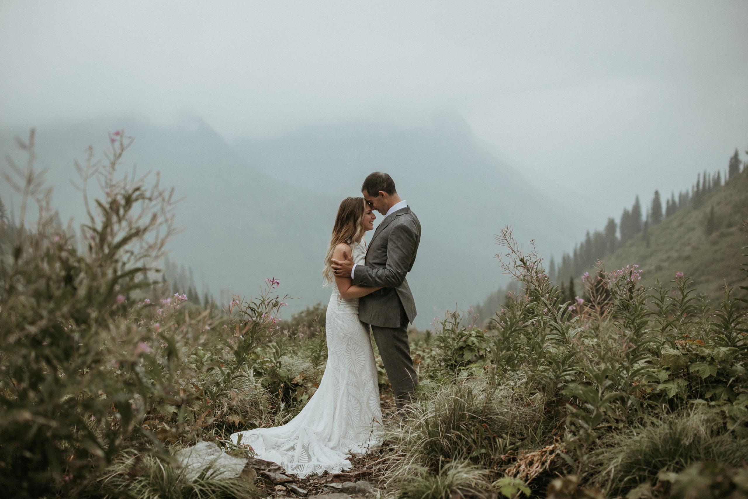 Bride and groom embracing in the rain and fog in the mountains of Glacier National Park