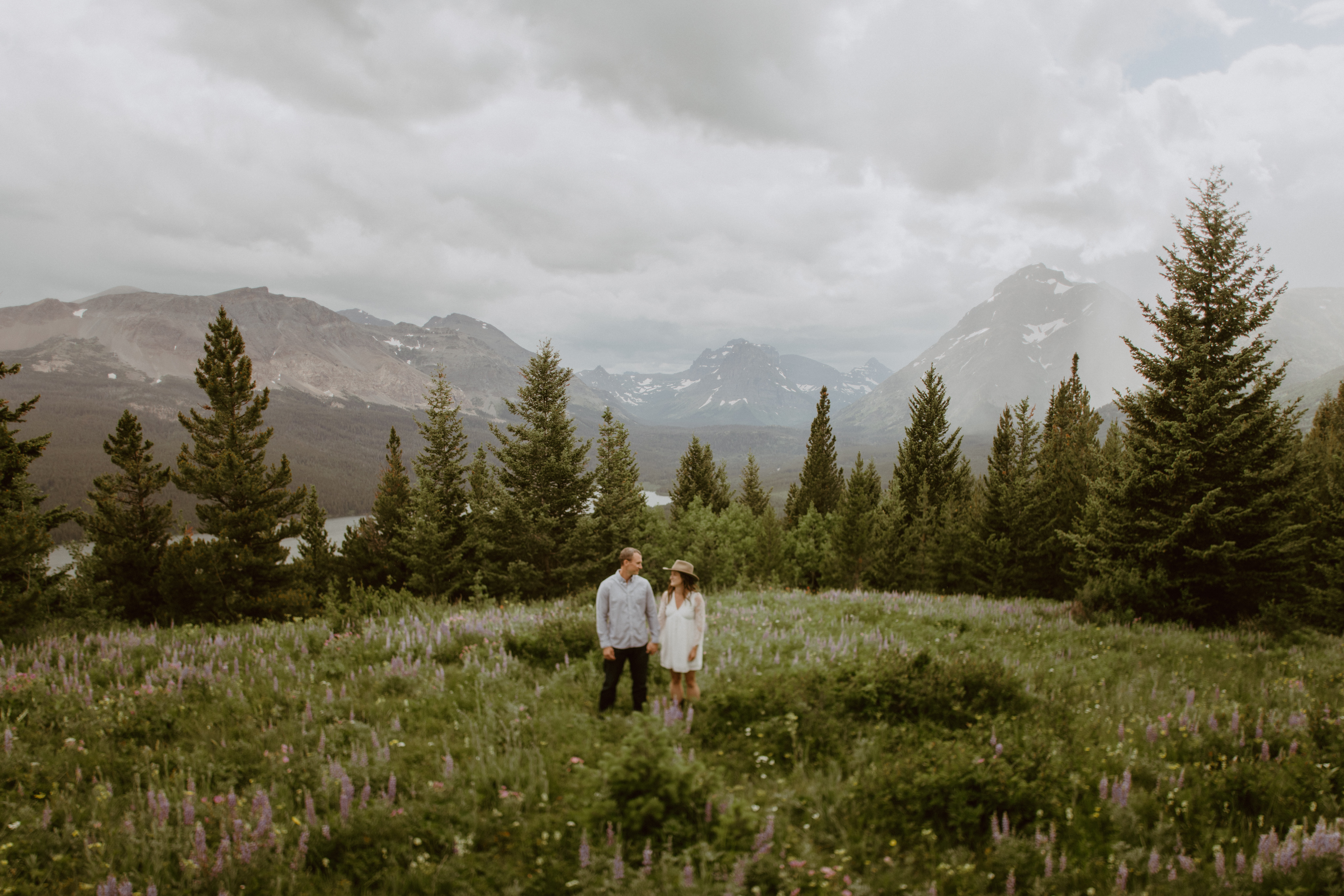 couple in wildflower field in mountains of glacier national park