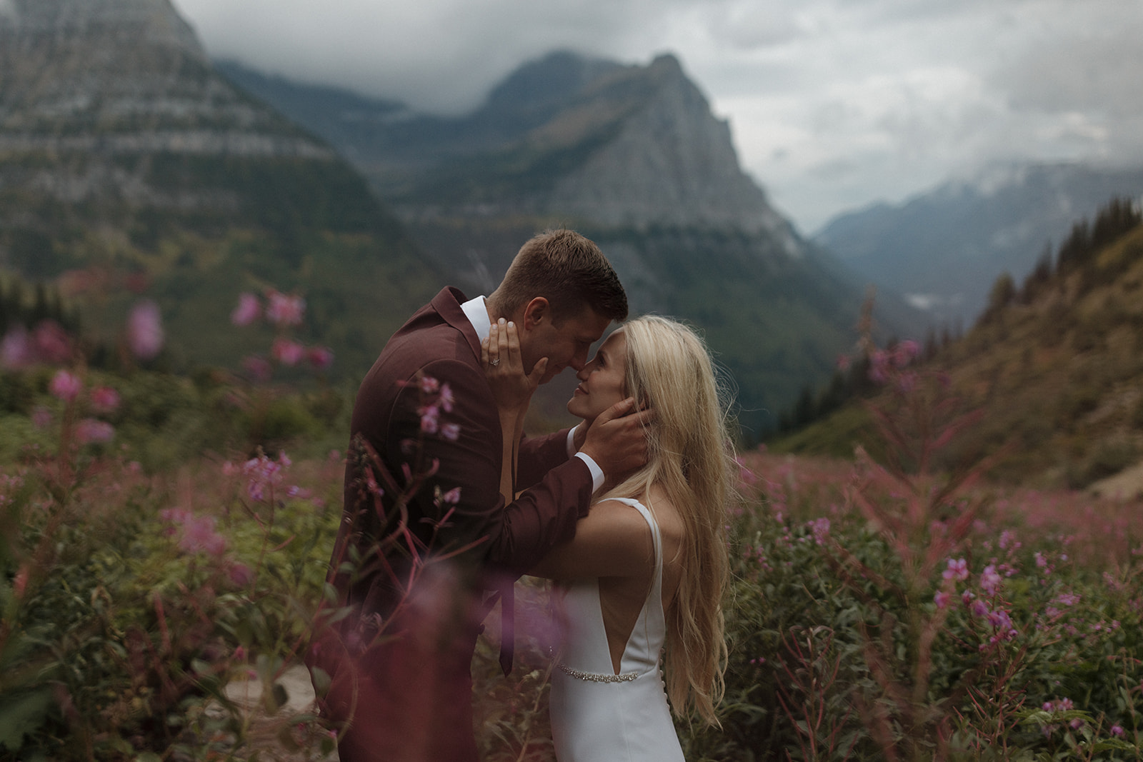 couple elopes in the moody mountains and wildflowers of glacier national park with family